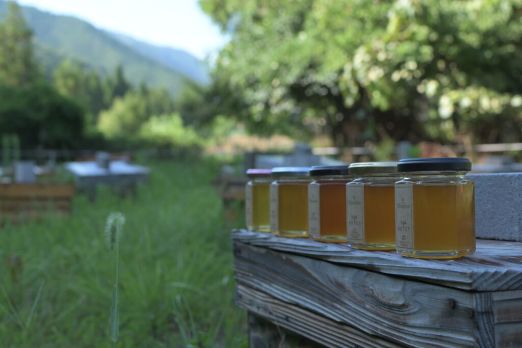 養蜂場の巣箱の上に5本のはちみつの瓶